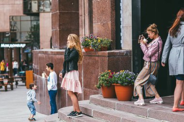 Moskova, Rusya - 7 Temmuz 2017. Bir grup insan Moskova 'daki McDonalds restoranının yakınındaki bir alışveriş merkezinin merdivenlerinde eğleniyor. Bir kız en tepede duruyor ve arkadaşının fotoğrafını çekiyor. 2 'nin altında