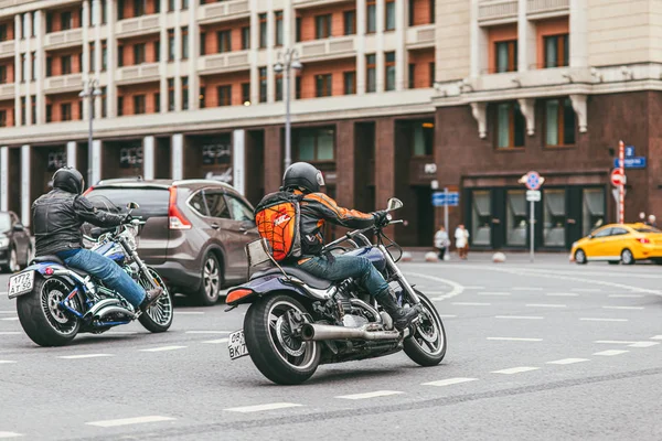 Москва, Россия - 7 июля 2017 г. 2 мотоциклиста в черных кожаных костюмах садятся на мотоциклы Harley Davidson и едут по дороге с машинами — стоковое фото