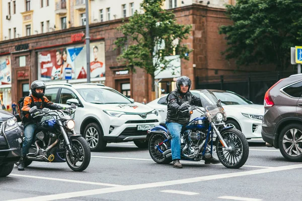 Москва, Россия - 7 июля 2017 г. 2 мотоциклиста в черных кожаных костюмах садятся на мотоциклы Harley Davidson и едут по дороге с машинами — стоковое фото