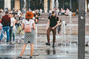 Moskova, Rusya - 1 Mayıs 2018. Şehirdeki aktif insanlar. Genç adam ve kadın etek giyer ve diğer insanlar şehir çeşmesine gider.
