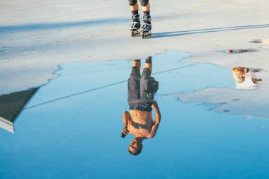 Moskova, Rusya - 9 AĞUSTOS 2014: Sokolniki Parkı 'nda çıplak gövde paten kayan genç bir adam. Su birikintisindeki yansıma