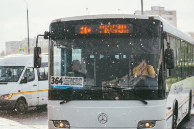 Moskova, Rusya - 2 Mayıs 2018: Bir belediye otobüsü şoförü oturur ve yolcu bekleyen bir durakta telefonu kullanır. Dışarıda yağmur yağıyor.
