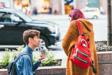 Moskova, Rusya - 7 Temmuz 2017. Genç adam kucağına oturur ve parlak mor saçlı bir kadına para verir.
