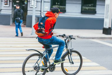 Moskova, Rusya - 7 Temmuz 2017: Kırmızı kapüşonlu genç bir adam elsiz bir bisikletle yaya geçidini geçiyor