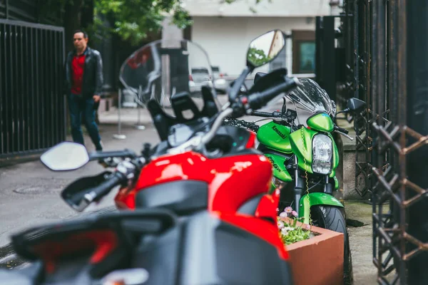 俄罗斯莫斯科- 2017年7月7日：绿色Kawasaki er-6n摩托车绑在红色摩托车旁边的金属围栏上，带有浅色DOF的选择性聚焦宏射 — 图库照片