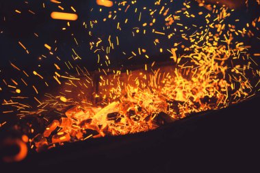 Bulanık hareket kıvılcımları bir şenlik ateşinin rüzgarıyla savruluyor. Yaz Kampı Konsepti. Seçici odak hareket bulanıklığı sığ DOF ile makro çekim