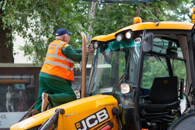 Moskova, Rusya - 7 Temmuz 2017: Moskova sokaklarındaki erkek işçiler büyük bir traktörün arka planına karşı onarım yapıyorlar