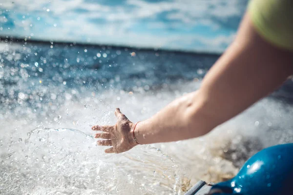 A womans hand touches the spray on a fast moving boat on the waves of a lake or sea — Stock Photo, Image