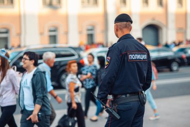 Moskova, Rusya - 10 Eylül 2017: üniformalı bir polis ve Moskova sokaklarında devriye gezen bir bere ve kalabalığın arkaplanını izleyen gözlemciler. Arka plan