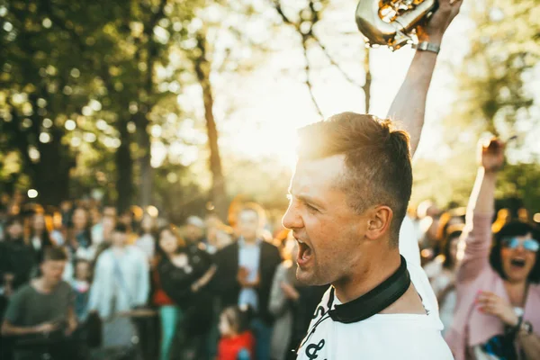 Moscú, Rusia - 9 DE MAYO DE 2018: Un joven músico con saxofón terminó su actuación, gritando en un alegre arrebato contra el telón de fondo de una multitud jubilosa en Gorky Park — Foto de Stock