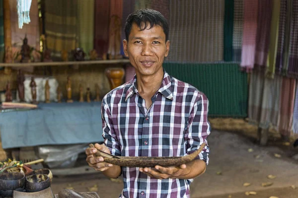 Siem Reap, Kambodža - 03 ledna 2017: Řemeslník na vesnici producentům palmového cukru ukazuje jeden z jeho dřevěné práce — Stock fotografie