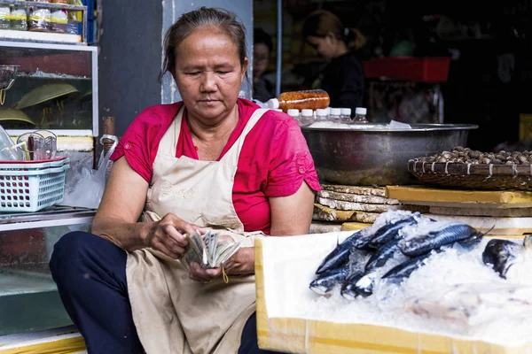 Phnom Penh, Kambodža - 30. prosince 2016: Žena kontrolovat denní výdělky na centrálním trhu hlavního města Kambodže. — Stock fotografie