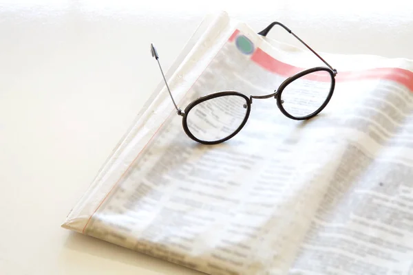 Газета с очками на коричневом фоне — стоковое фото