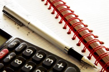 Hesap makinesi üstünde defter kalem ile