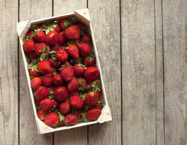 Taze olgun çilekler hasır sepetin içinde beyaz kırsal masada.