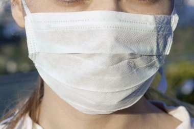 Şehirdeki hava kirliliği ya da virüs salgını yüzünden maske takan bir kadın.