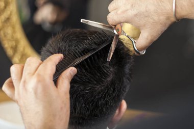  Erkek kuaför müşteriye servis yapıyor, saç kesimini makine ve tarak kullanarak yapıyor..