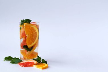 Detox narenciye kokteyli. Sağlıklı bir yaşam tarzı. Beyaz zemin üzerinde nane yapraklı taze portakal dilimleri ve kopyalama alanı olan kokteyl..