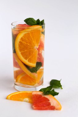 Bir bardak portakal dilimli kokteyl ve beyaz arka planda nane yapraklı greyfurt. Detox narenciye kokteyli. sağlıklı yaşam tarzı.
