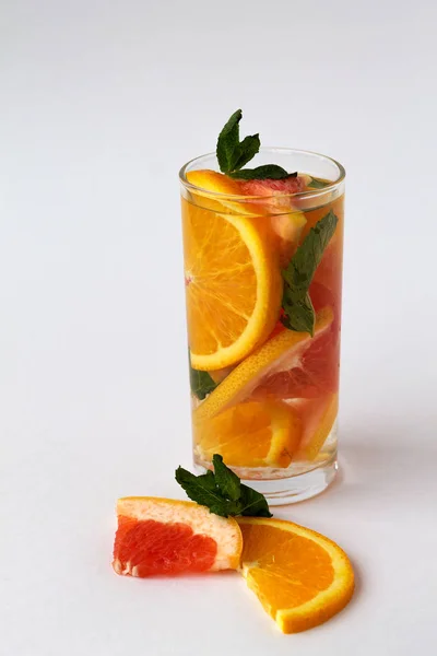 glass of refreshing orange cocktail with green mint on white background. Detox citrus cocktail. healthy lifestyle.