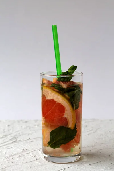 red grapefruit cocktail with green mint on white background. Detox citrus cocktail. healthy lifestyle.