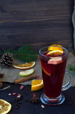 Kışın ve sonbaharın sıcak içecekleri. portakal, elma ve baharat dilimli şarap, tarçın ve anason yıldızı ahşap bir masada kış süslemeleri ile. dikey