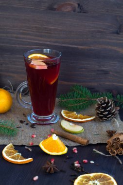 Sıcak sıcak şarap, portakal, elma ve baharat dilimleri, tarçın ve anason yıldızı ile birlikte koyu ahşap arka planda kış süslemeleri ile birlikte. Kışın ve sonbaharın sıcak içecekleri. kopyalama alanı. dikey
