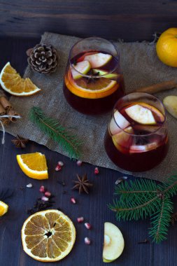 Sonbahar ya da kış hala hayattadır. İki kadeh kırmızı şarap, portakal, elma ve baharatla ahşap bir masada kış süslemeleri ile birlikte. Kışın ve sonbaharın sıcak içecekleri. Üst Manzara. Boşluğu kopyala