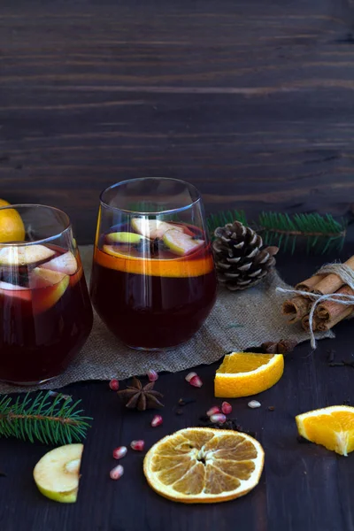 hot drinks of winter and autumn. autumn or winter still life. two glasses with hot mulled wine with orange, apple and spices on a wooden background with winter decorations.