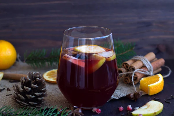 スパイスと赤ワインのガラス リンゴとスパイスを中心に赤ホット モルドワインのグラスに オレンジのスライスを加えた木製のテーブルの上にシナモンスティックが付いています 水平だ冬と秋のホットドリンク — ストック写真