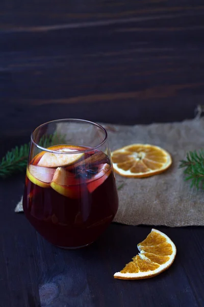 オレンジとバラップのスライスと木製のテーブルの上にリンゴとスパイスと赤マルチワインのガラス 冬の休日の伝統的な飲み物 — ストック写真