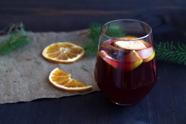 オレンジとブラップのスライスと木製のテーブルの上にリンゴとスパイスと赤マルチワインのガラス 冬の休日に伝統的な飲み物 コピースペース水平 — ストック写真