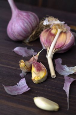 Tahta arka planda taze sarımsak. Karanlık bir masada soyulmamış ve soyulmamış taze sarımsak. sağlıklı ve sağlıklı yiyecekler. düşey yönelim.