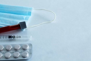 Tıbbi koruyucu maske, şırınga, beyaz arka planda izole edilmiş haplı kan test tüpü. Sağlık sigortası. Coronavirus karantinası, hijyen konsepti. Koronavirüsü önle. Üst Manzara. Boşluğu kopyala