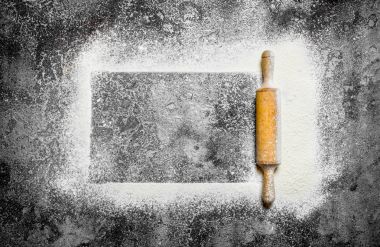 Fırın arka plan. Çerçeve bir oklava ile elenmiş un. Rustik arka plan üzerinde.