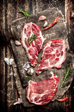 Çiğ et arka plan. Baharat ve otlar ile çiğ biftek parçaları. Ahşap arka plan üzerinde.