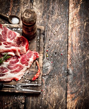 Çiğ et arka plan. Baharat ve otlar ile çiğ biftek parçaları. Ahşap arka plan üzerinde.