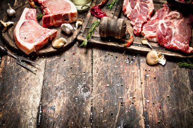Çiğ et arka plan. Çeşitli otlar ve baharatlar ile çiğ domuz pirzolası.