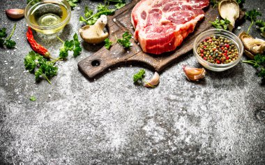 Çiğ et arka plan. Biteviye-in pişmemiş Domuz pirzola kokulu baharatlar ve taze otlar ile. Rustik arka plan üzerinde.