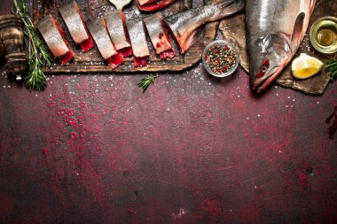 Baharat ve otlar ile taze alabalık parçaları. Rustik arka plan üzerinde.