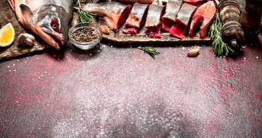 Baharat ve otlar ile taze alabalık parçaları. Rustik arka plan üzerinde.