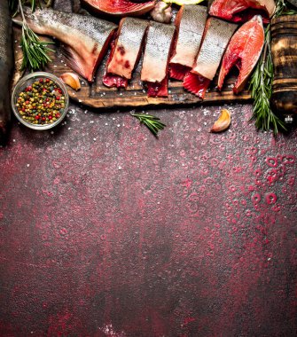 Baharat ve otlar ile taze alabalık parçaları. Rustik arka plan üzerinde.