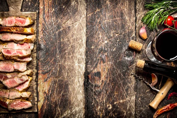 Mięso grill. Kawałki mięsa wieprzowego z grilla z przyprawami i czerwone wino. Na starym drewnianym stole. — Zdjęcie stockowe