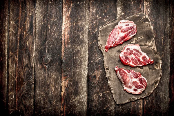 Fondo de carne cruda. Trozos de carne en la vieja junta. Sobre fondo de madera . —  Fotos de Stock