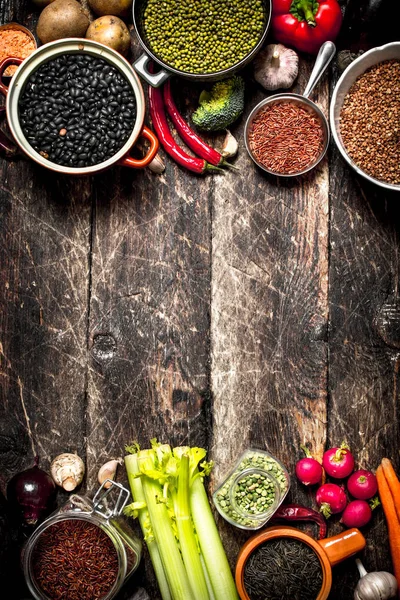 Comida orgánica. Una variedad de frijoles con verduras frescas y especias. En la vieja mesa de madera . — Foto de Stock