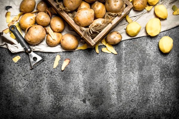 Die geschälten Kartoffeln mit einer alten Holzkiste. auf rustikalem Hintergrund. — Stockfoto