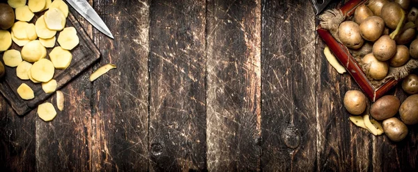 Нарезанная картошка на старой деревянной доске. На деревянном фоне . — стоковое фото
