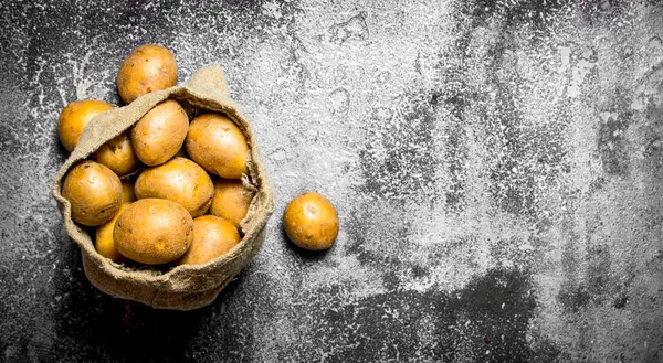 Kartoffeln in einem alten Sack. auf rustikalem Hintergrund. — Stockfoto