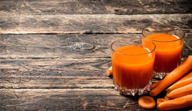 Taze havuç suyu. Eski ahşap masa üzerinde.