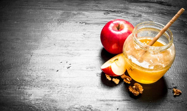 Honey background. Honey in pot with slices of ripe apples and nuts.